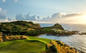 Ein Küsten-Golfplatz mit Blick auf den Ozean und einem wolkenlosen Himmel.