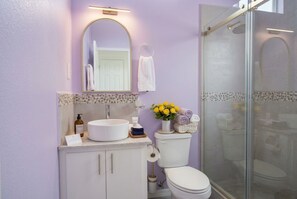 Une salle de bain avec un lavabo, des toilettes et une douche, le tout de couleur blanche.