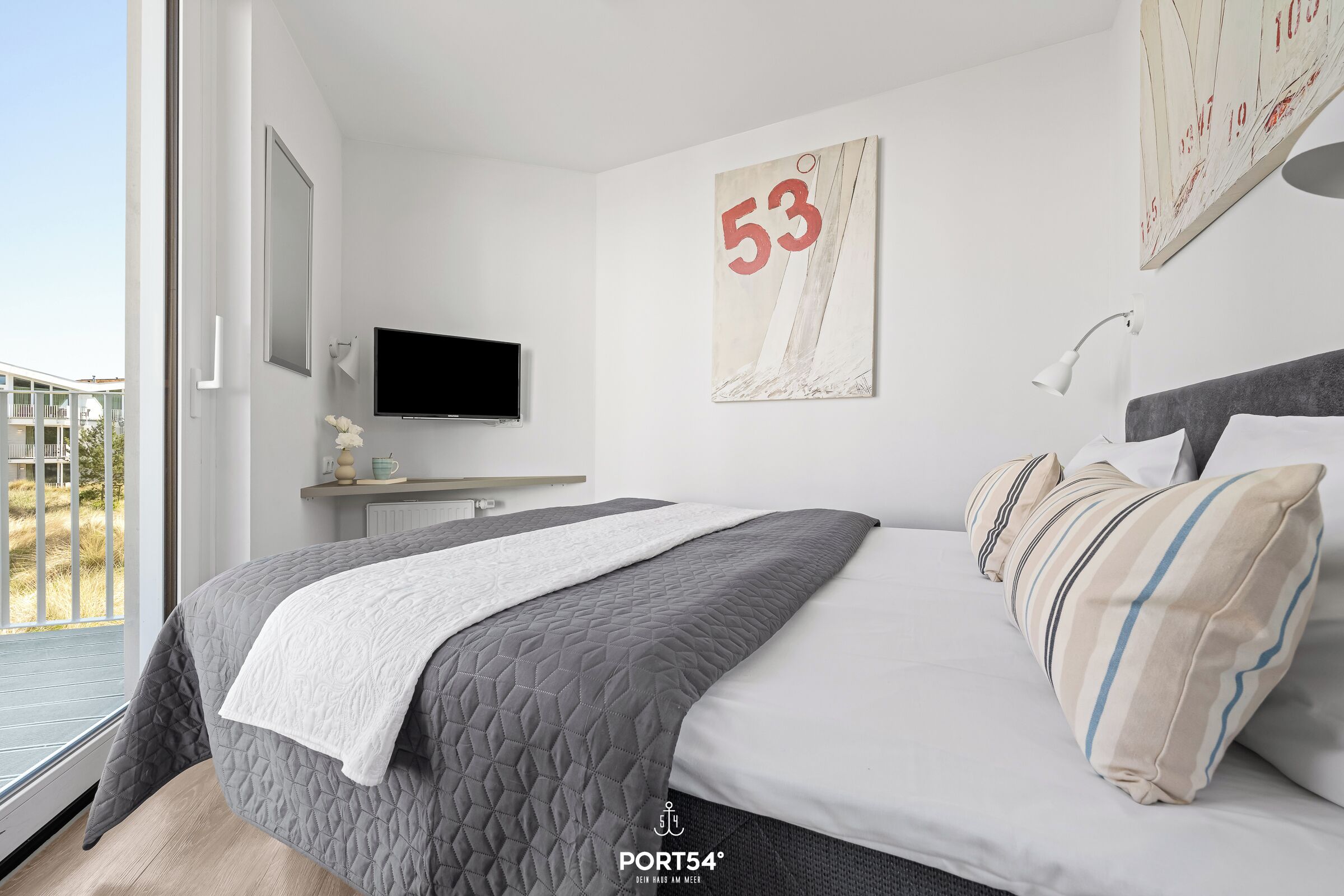 A modern bedroom with a bed, a TV, a painting, and a window.
