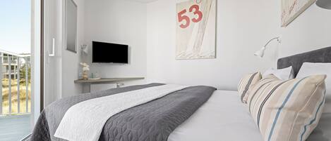 A modern bedroom with a bed, a TV, a painting, and a window.