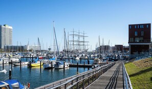 Ein Yachthafen mit mehreren angestaubten Booten, einer Holzsteganlage und Gebäuden im Hintergrund.