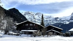 A wooden chalet with a snow-covered roof, surrounded by a snowy landscape and mountains. - Chalet Rotebächli Appartement/Fewo, Bad, WC, 2 Schlafräume 4-Bettwohnung by Interhome (Lenk)