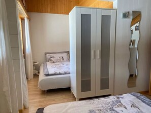 A bedroom with a bed, a wardrobe, and a mirror. - Chalet Rotebächli Appartement/Fewo, Bad, WC, 2 Schlafräume 4-Bettwohnung by Interhome (Lenk)