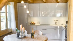 A modern kitchen with white cabinets, a dining table with candles, and a bottle of champagne. - Chalet Rotebächli Appartement/Fewo, Bad, WC, 2 Schlafräume 4-Bettwohnung by Interhome (Lenk)