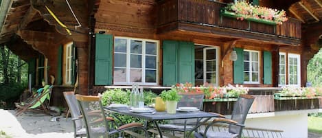 A wooden chalet with a balcony, outdoor seating, and flower boxes.