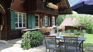 A wooden chalet with a balcony, a table and chairs set outside, and a garden area. - Chalet Maru Appartement/Fewo, Dusche oder Bad, WC, 3 Schlafräume 7-Bett-Wohnung by Interhome (Lenk)