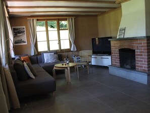 A living room with a sofa, a television, a fireplace, and a dining table. - Chalet Maru Appartement/Fewo, Dusche oder Bad, WC, 3 Schlafräume 7-Bett-Wohnung by Interhome (Lenk)