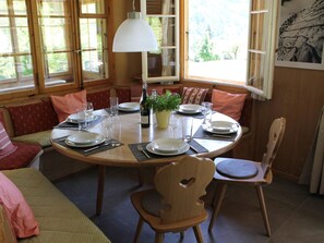 A dining area with a round table set for four, surrounded by wooden chairs and benches. - Chalet Maru Appartement/Fewo, Dusche oder Bad, WC, 3 Schlafräume 7-Bett-Wohnung by Interhome (Lenk)