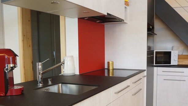 A modern kitchen with a black countertop, stainless steel sink, and white cabinetry. - Lischenhaus 2 - Wohnung Flösch Appartement/Fewo, Dusche, WC, 1 Schlafraum by Interhome (Lenk)
