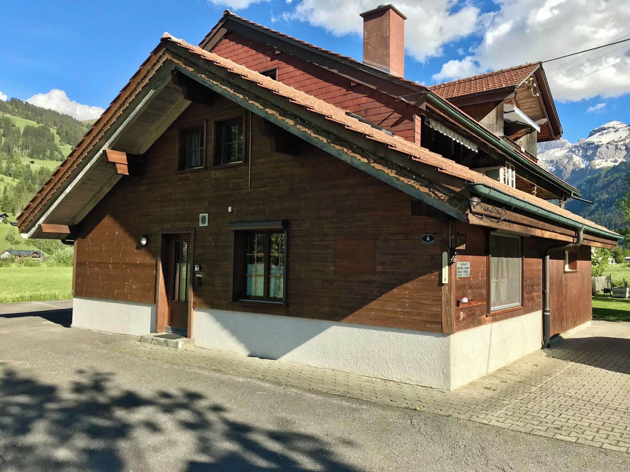 A two-story wooden house with a sloped roof, a chimney, and a small balcony.