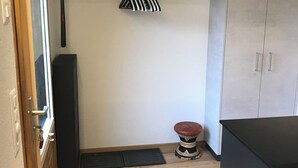 A compact kitchen with a wooden countertop, a black cabinet, a small stool, and a hanging rack with a striped item. - Lischenhaus 2 - Wohnung Flösch Appartement/Fewo, Dusche, WC, 1 Schlafraum by Interhome (Lenk)