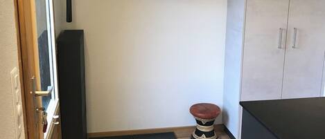 Una cocina compacta con encimera de madera, un armario negro, un taburete pequeño y un tendedero con un artículo a rayas.