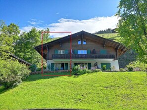 A two-story chalet with a balcony, surrounded by lush greenery and a clear sky. - Chalet Flöschhorn Appartement/Fewo, Bad, WC, 3 Schlafräume by Interhome (Lenk)