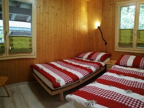 A wooden room with two beds, each with a red and white checkered bedspread and matching pillows. - Chalet Flöschhorn Appartement/Fewo, Bad, WC, 3 Schlafräume by Interhome (Lenk)