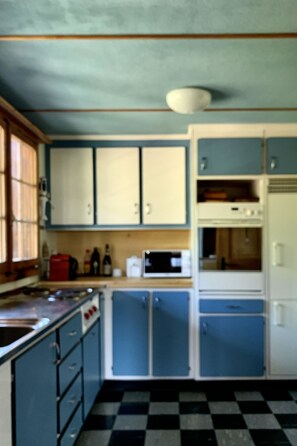 Eine Küche mit blauen Schränken, einer Mikrowelle und einem Kühlschrank.