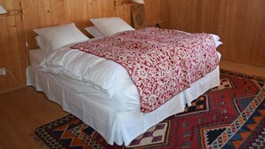 A wooden-paneled room with a bed, two bedside lamps, and a patterned rug. - Steirösli 1. & 2. Stock Appartement/Fewo, Dusche und Badewanne, 4 oder mehr Schl by Interhome (Lenk)