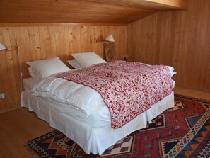 Ein Zimmer mit Holzwänden, einem Bett, zwei Nachttischlampen und einem gemusterten Teppich.