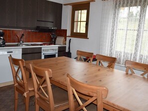 A kitchen with a wooden table and chairs, a stove, and a window with curtains. - Brandegg 4 Appartement/Fewo, Dusche oder Bad, WC 5-Bett-Wohnung by Interhome (Lenk)