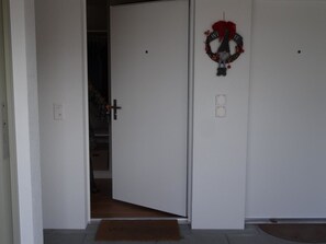 Una porta chiusa con un zerbino e una ghirlanda appesa al muro.