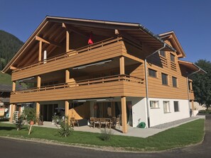 Ein zweistöckiges Holzhaus mit Balkon, überdachter Terrasse und Garage.