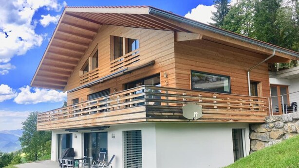 A modern two-story house with a wooden facade, a balcony, and a satellite dish. - Chalet Coco Appartement/Fewo, Dusche, WC, 3 Schlafräume 6-Bett-Wohnung by Interhome (Lenk)