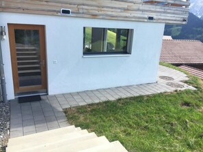 Ein modernes Gebäude mit einer Holztür, einem Fenster und einer Treppe, die zum Eingang führt.