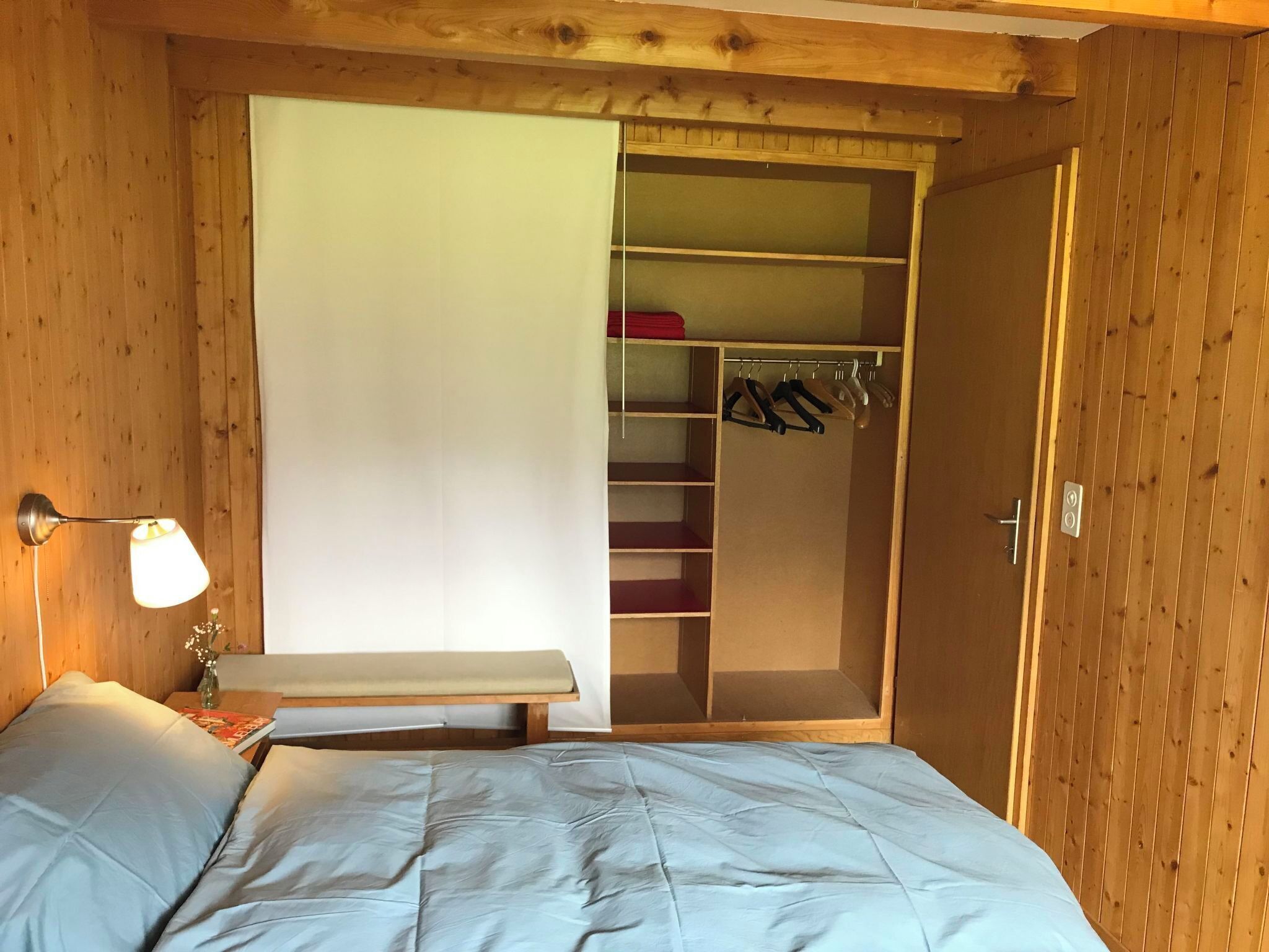 Une chambre à coucher comprenant un lit, une table de chevet, une lampe, une armoire et un placard.