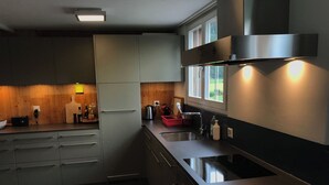 Eine moderne Küche mit grauen Schränken, einer Edelstahl-Spüle und einem Fenster über der Arbeitsfläche.