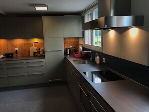 Eine moderne Küche mit grauen Schränken, einer Edelstahl-Spüle und einem Fenster über der Arbeitsfläche.