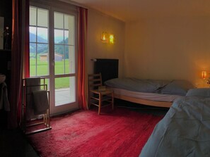 A room with a bed, a chair, a desk, and a window with curtains. - Burgbüel # 1 Appartement/Fewo, Dusche oder Bad, WC, 4 oder mehr Schlafräume by Interhome (Lenk)