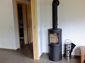 Um interior moderno com uma lareira a lenha, uma porta que dá para outro espaço e um recipiente metálico no chão.