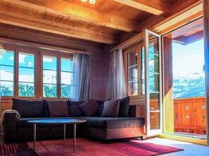 A cozy room with a sectional sofa, a small table, and large windows offering a view of the outdoors. - Lemberg Ferienhaus, Dusche und Bad, WC, 3 Schlafräume 6-Bett-Ferienhaus by Interhome (Lenk)