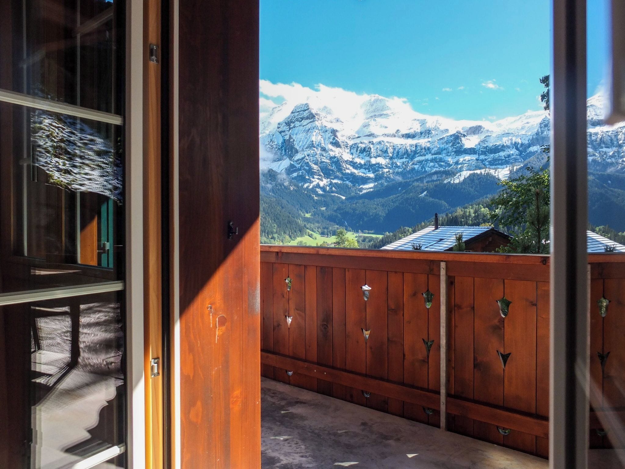 A wooden balcony with a view of snow-capped mountains.