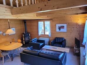 Ein Holzinnenraum mit Kamin, Sitzgruppe und Esstisch.