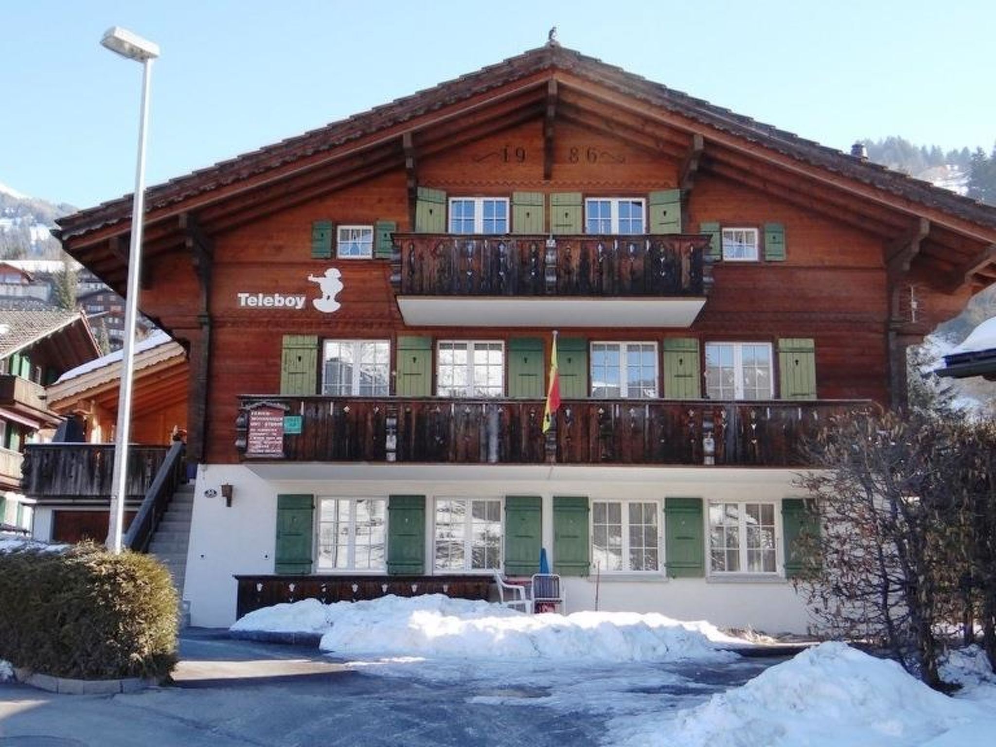 A two-story wooden building with a balcony, a sign for 'Teleboy,' and a flag.
