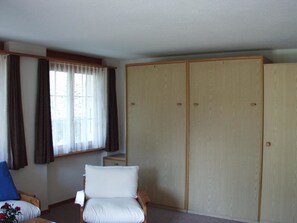 Quarto com uma cama de solteiro, guarda-roupa e janela com cortinas.