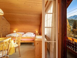 A wooden cabin room with two beds, a table, and a chair. - Berna 2. Stock Appartement/Fewo, Bad, WC, 2 Schlafräume 4-Bettwohnung by Interhome (Lenk)