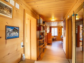 A wooden interior with a hallway, bookshelves, a dining area, and a fireplace. - Berna 2. Stock Appartement/Fewo, Bad, WC, 2 Schlafräume 4-Bettwohnung by Interhome (Lenk)