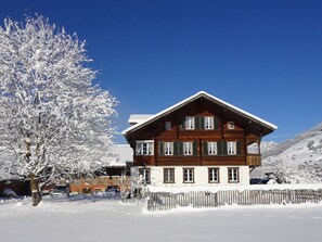 A two-story wooden chalet with a sloped roof, surrounded by snow-covered trees and a clear blue sky. - Bühlerhof Appartement/Fewo, Dusche oder Bad, WC, 3 Schlafräume 6-Bett-Wohnung by Interhome (Lenk)