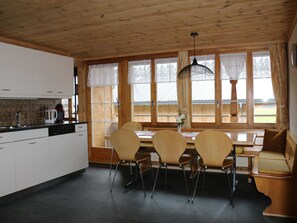 A wooden interior with a kitchen, dining table, and chairs. - Bühlerhof Appartement/Fewo, Dusche oder Bad, WC, 3 Schlafräume 6-Bett-Wohnung by Interhome (Lenk)