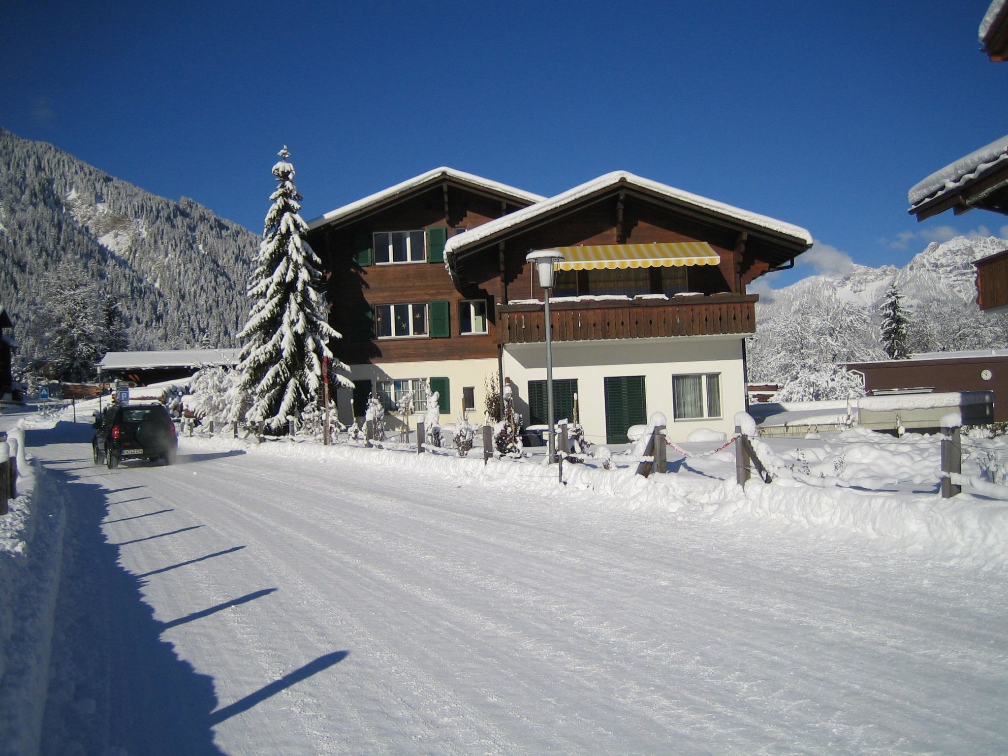 A snow-covered building with a wooden facade, a balcony, and a clear sky.