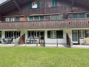 Ein zweistöckiges Holzhaus mit Balkon, Außenbereich und gepflegtem Rasen.