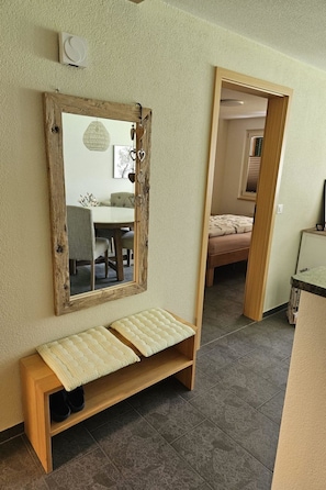 A room with a wooden bench, a mirror with a rustic frame, and a doorway leading to another room. - Bergecho EG Mitte Appartement/Fewo, Bad, WC, 1 Schlafraum 2 Bettwohnung by Interhome (Lenk)