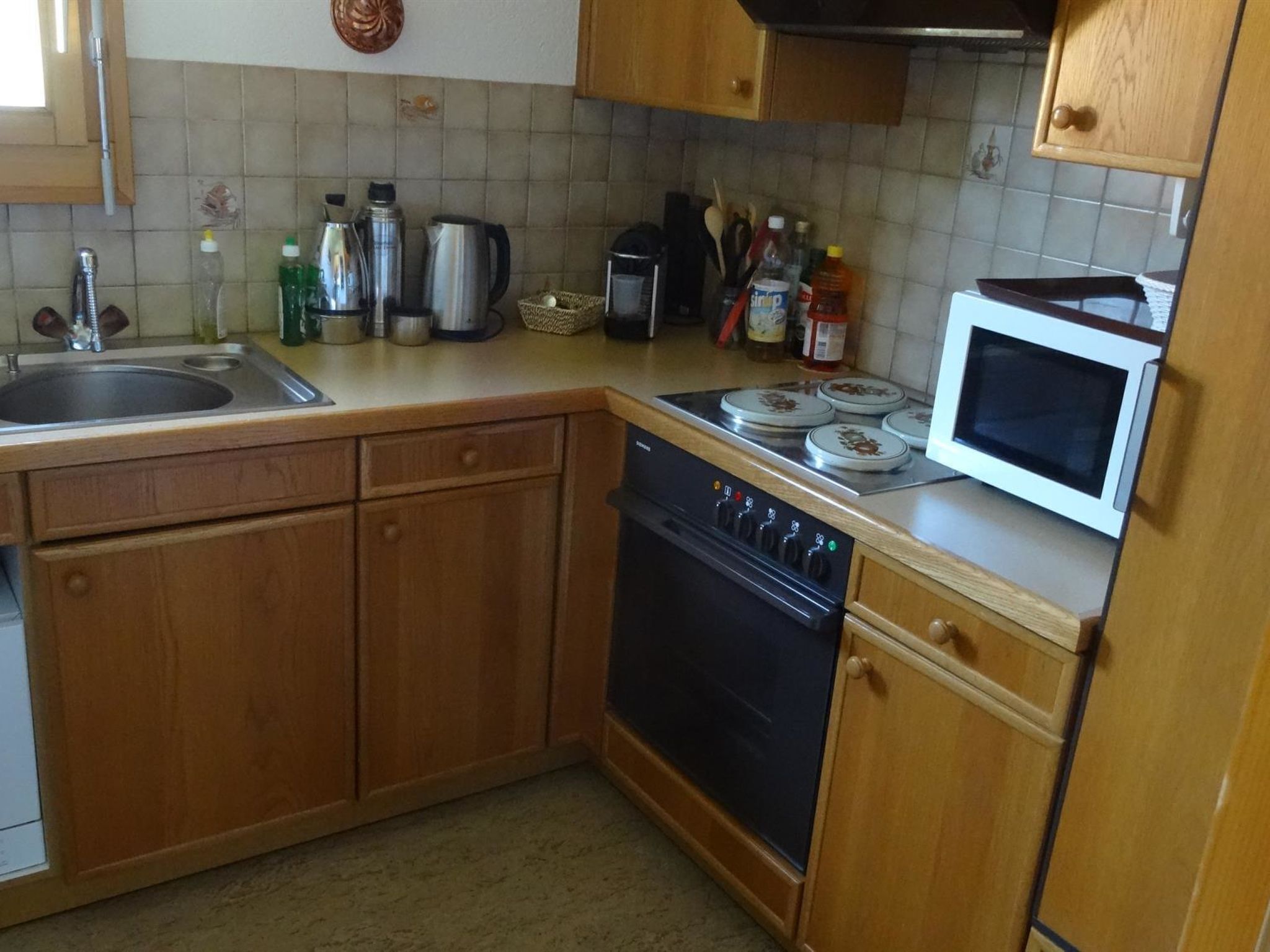 Une cuisine avec des meubles de rangement en bois, un évier, une cuisinière et un four à micro-ondes.