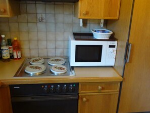 A kitchen with a Siemens stove, a Bosch microwave, and various kitchen items on the counter. - Siebenbrunnen Appartement/Fewo, Bad, WC, 1 Schlafraum 2-Bettwohnung by Interhome (Lenk)