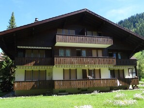 A multi-story wooden chalet with balconies, a covered front porch, and a mountain backdrop. - Siebenbrunnen Appartement/Fewo, Bad, WC, 1 Schlafraum 2-Bettwohnung by Interhome (Lenk)