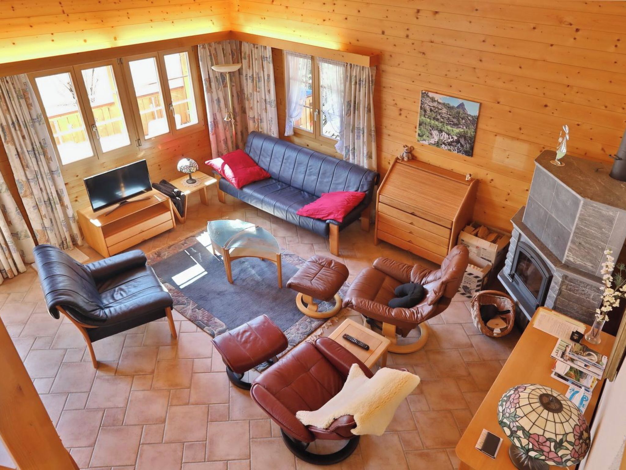 A cozy living room with a sofa, chairs, a TV, and a fireplace.