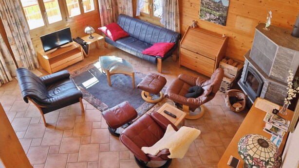 Una sala de estar acogedora con un sofá, sillones, un televisor y una chimenea.