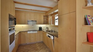 Una cocina compacta con armarios de madera, horno integrado, lavavajillas y ventana sobre el fregadero.