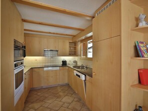 A compact kitchen with wooden cabinets, a built-in oven, a dishwasher, and a window above the sink. - Hohliebestrasse 24 Appartement/Fewo, Dusche und Bad, WC, 2 Schlafräume by Interhome (Lenk)